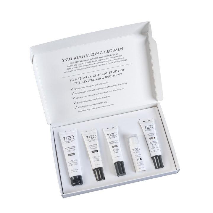 Opened TiZO Photoceutical Skincare Skin Revitalizing Regimen box with TiZO Mini Gentle Amino Gel Cleanser, TiZO Mini Complexion Brightener, TiZO Mini Daily Moisture, TiZO Mini Eye Renewal Non-Tinted, and TiZO Mini AM Replenish Lightly Tinted.