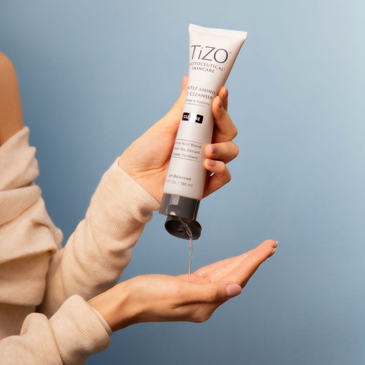 woman squeezing TiZO Gentle Amino Gel Cleanser tube into hand.