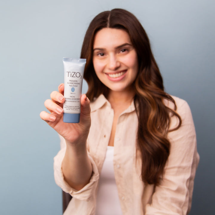 woman holding TiZO 2 Non-Tinted tube in hand.