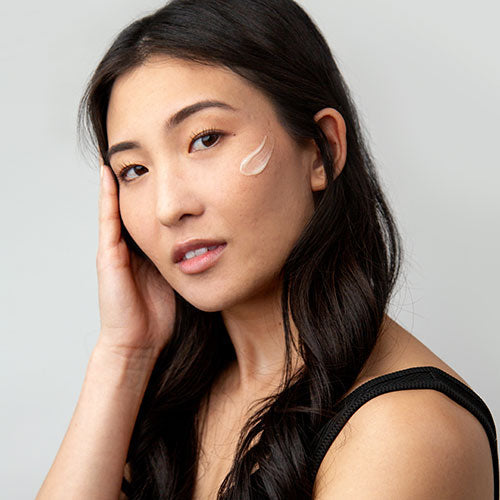 model with long, dark hair with a TiZO peptide serum swatch on her cheekch 