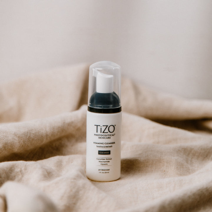 TiZO Mini Foaming Cleanser 1 FL. OZ. bottle sitting on linen fabric.